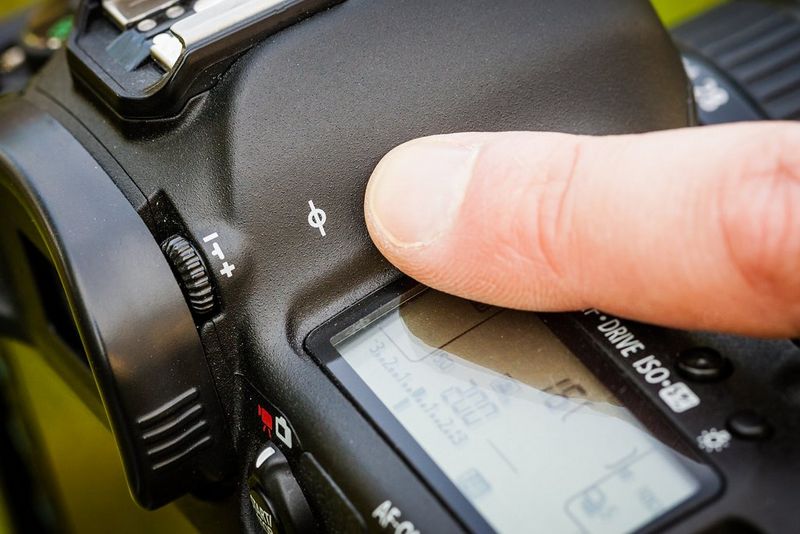 A finger pointing at a mark on the camera body with a circle crossed with a line.