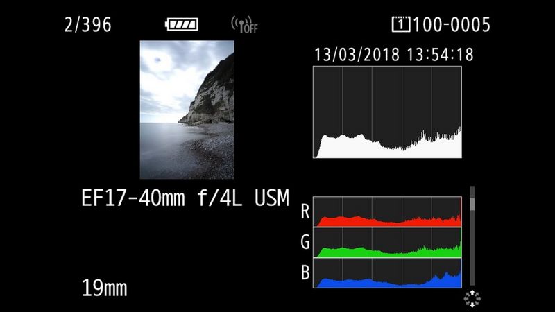 A screengrab from the camera showing a picture of a stony beach with a hill and a cloudy sky in the background. On the right a histogram and RGB scale are showing. 