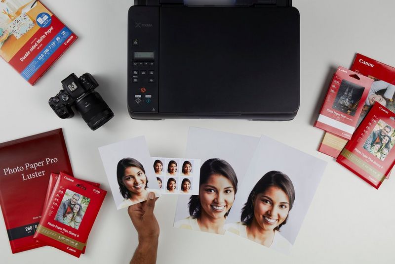 Een bovenaanzicht van een PIXMA G650-printer omgeven door fotopapier, geprinte foto's en een Canon-camera.