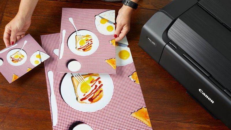 Un photographe examine des impressions couleur éclatantes de divers formats, toutes obtenues avec la PIXMA PRO-200