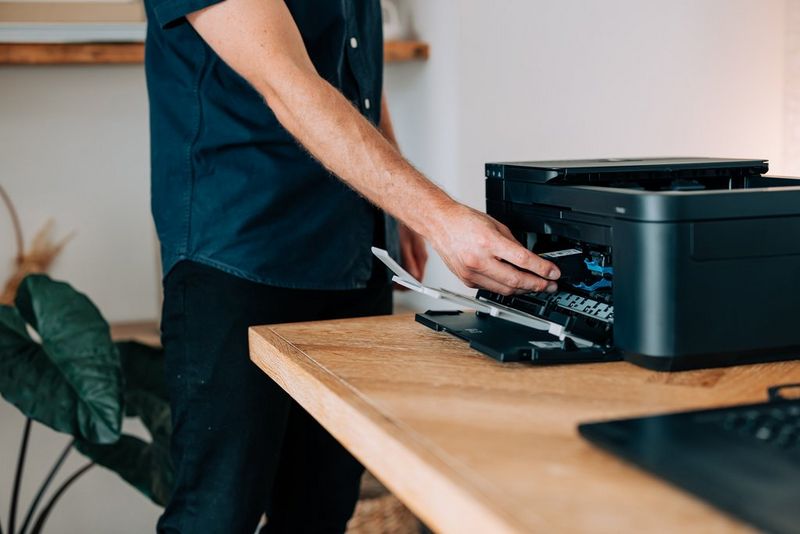 A man reaches into the front of a Canon PIXMA printer.