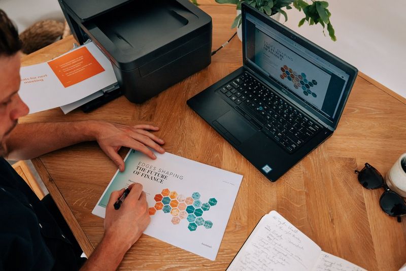 A person writing on a printed slide from a presentation, with a Canon printer on the desk alongside.