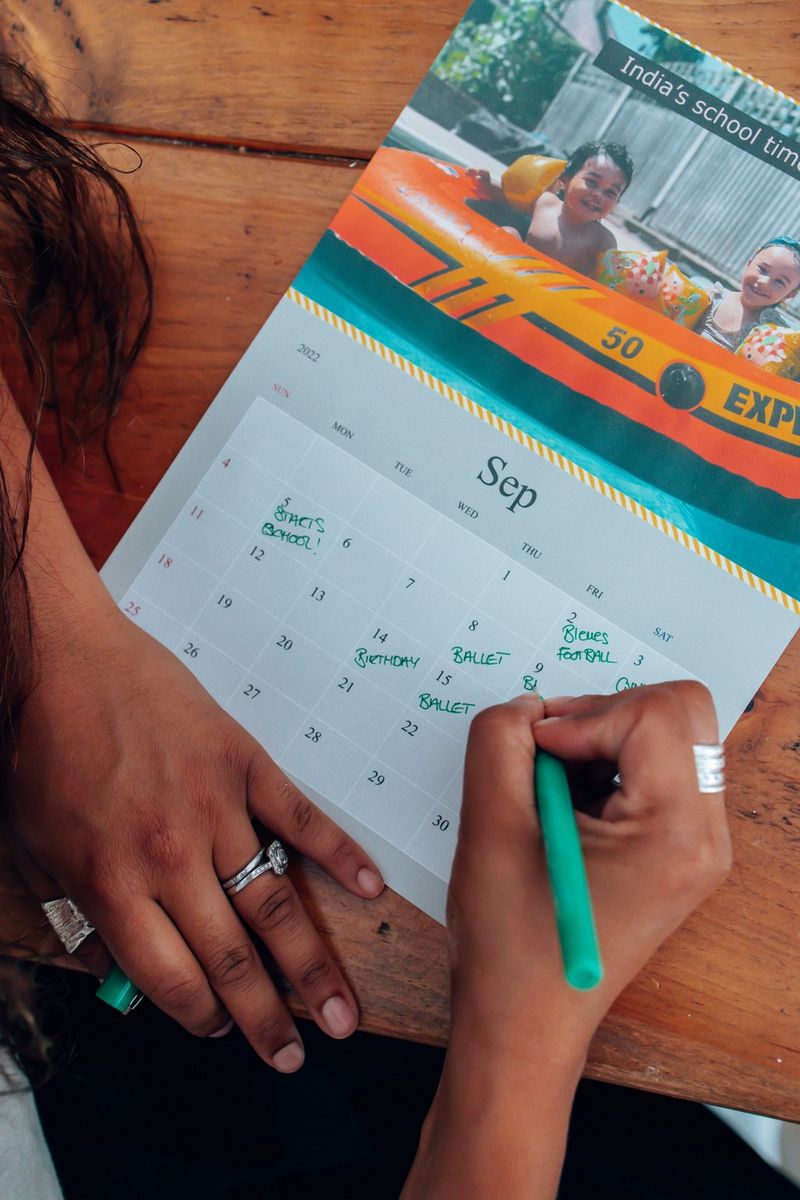 A top-down image of a person filling in dates for the month of September on a homemade calendar.