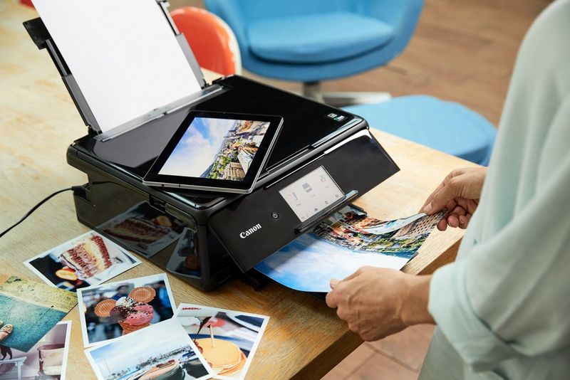 משתמש מחזיק תדפיס הנפלט ממדפסת Canon PIXMA. על השולחן ליד המדפסת מונחות מספר הדפסות נוספות.
