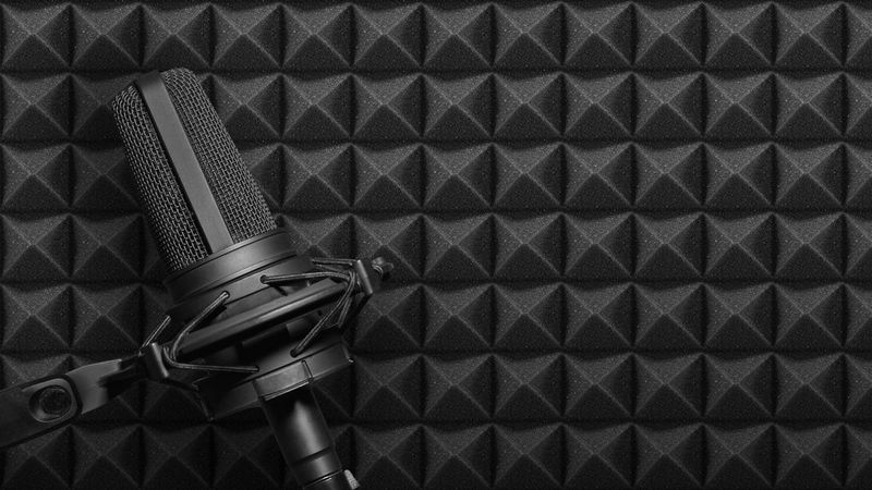 A recording studio microphone on black acoustic foam background.