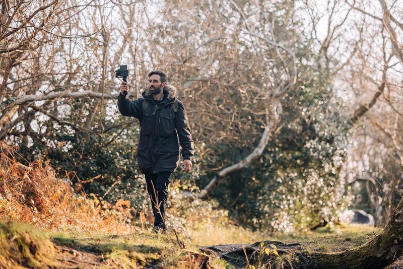 Мужчина идет по лесу и снимает себя на камеру PowerShot G7 X Mark III.