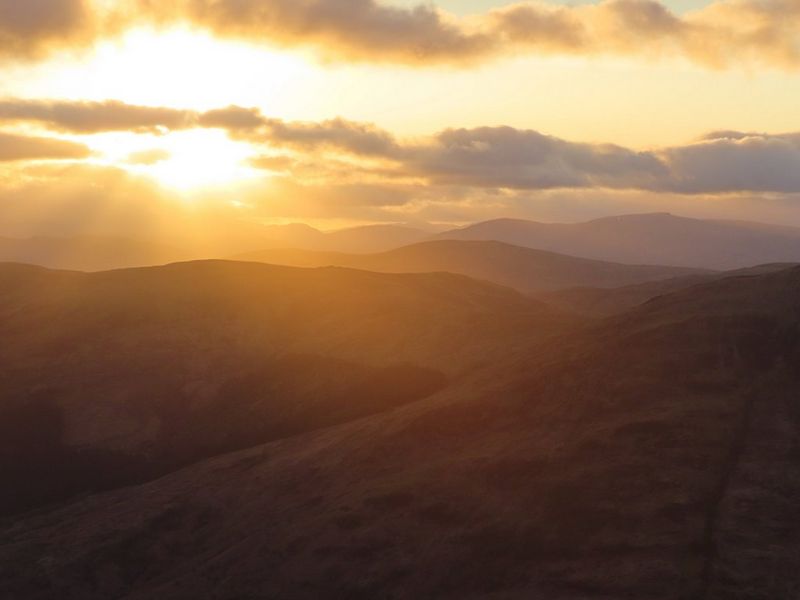 השמש שוקעת מעל לנוף של הרים נמוכים. צולם באמצעות Canon PowerShot SX740 HS LITE EDITION.
