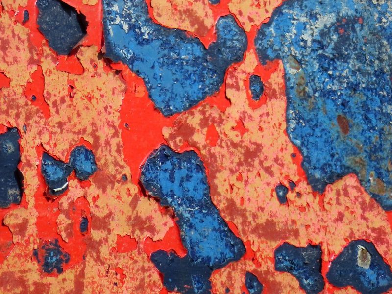 צילום תקריב של החלודה על גוף סירה מציג "קשקשים" של צבע אדום וכחול, בעלי מרקם מתכתי. צולם באמצעות Canon PowerShot SX740 HS LITE EDITION.