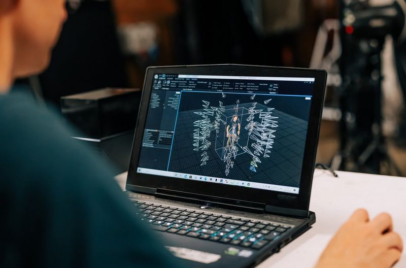 Lo schermo di un laptop che mostra il modello 3D di una figura in piedi circondata da una rappresentazione delle fotocamere.