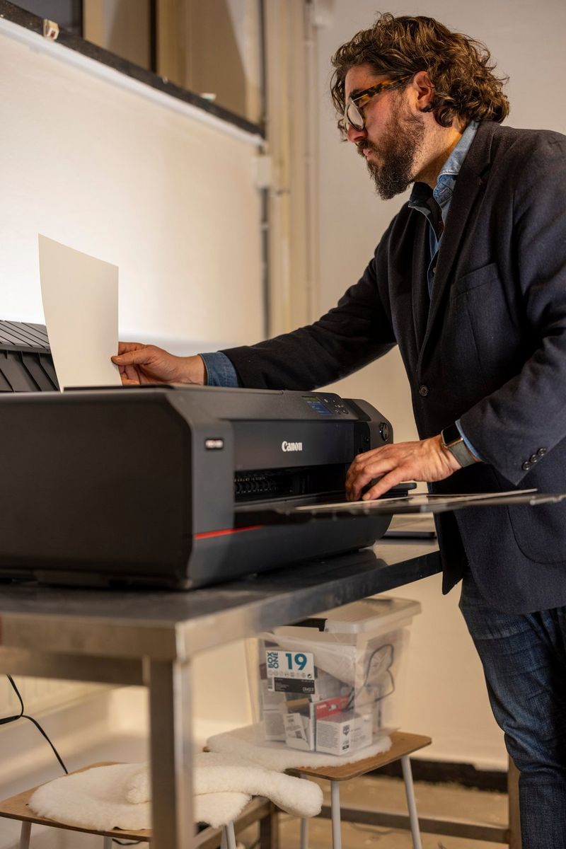 Ahmet Polat feeds a sheet of paper into a Canon imagePROGRAF PRO-1100 printer.
