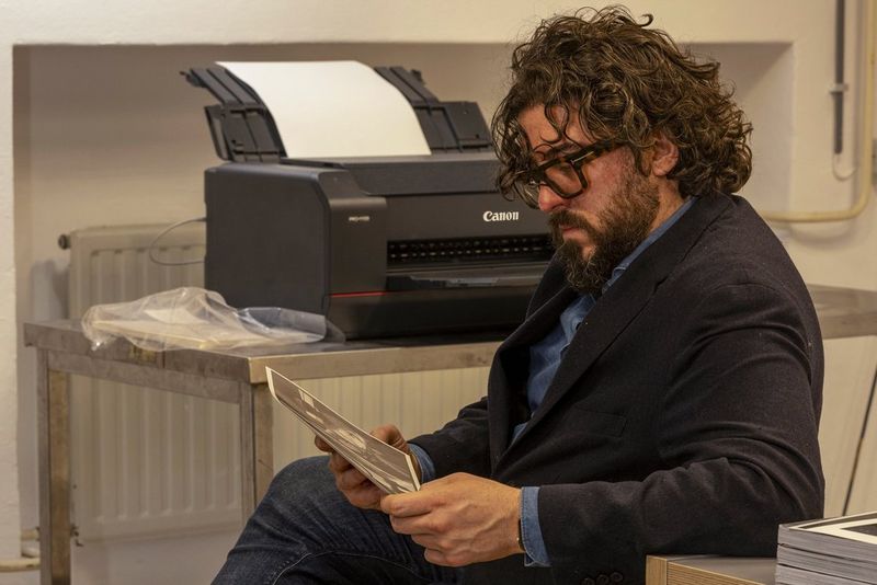 Ahmet Polat examines a print from a Canon imagePROGRAF PRO-1100 printer on a table next to him.