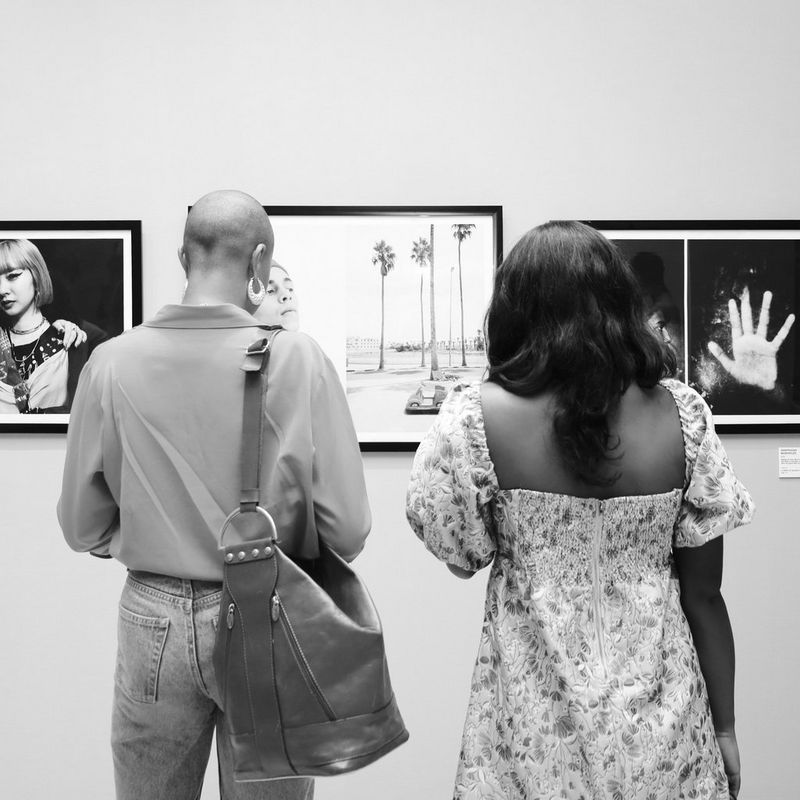 The backs of two people as they stand looking at photographs displayed at the opening of the 2022 Africa Foto Fair.