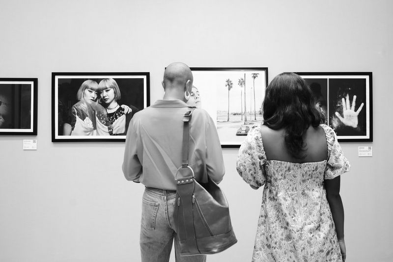 Due persone di spalle che guardano le fotografie esposte all'inaugurazione dell'Africa Foto Fair 2022.