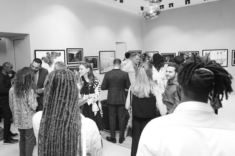 Una sala della galleria piena di persone che parlano tra loro.