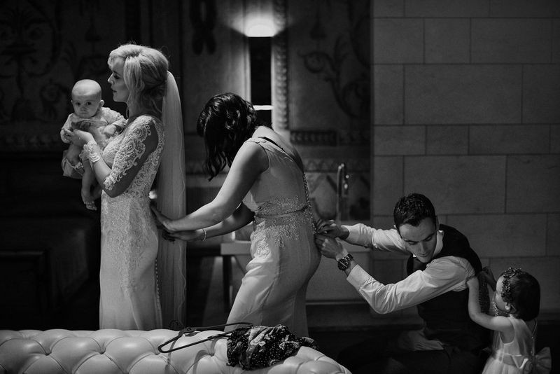 Four members of a wedding party in a line, each adjusting the person in front's clothing. Taken by Canon Ambassador Adam Trzcionka.