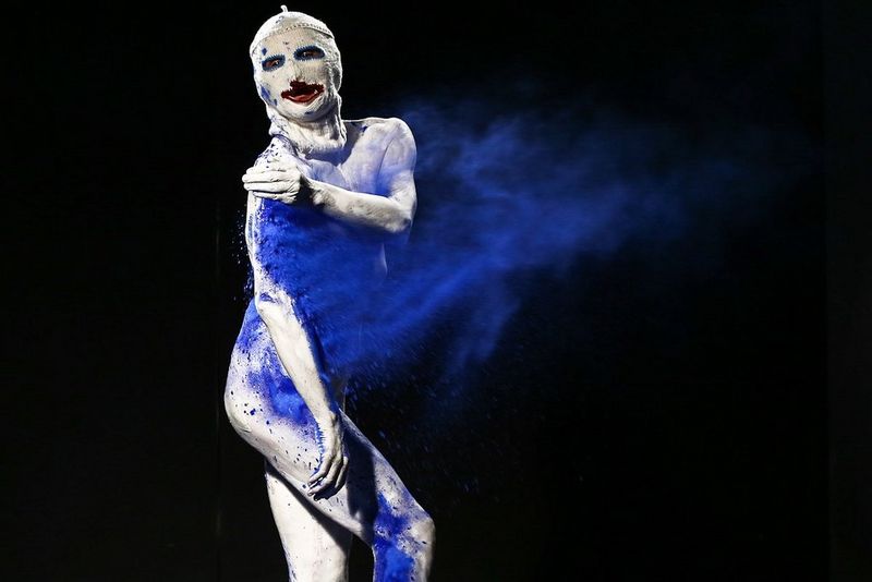 A performer wearing a theatrical mask uses their hand to slam blue powder against their shoulder, creating a sense of movement and flow. Taken on a Canon EOS-1D X by Canon Ambassador Aljoša Rebolj.