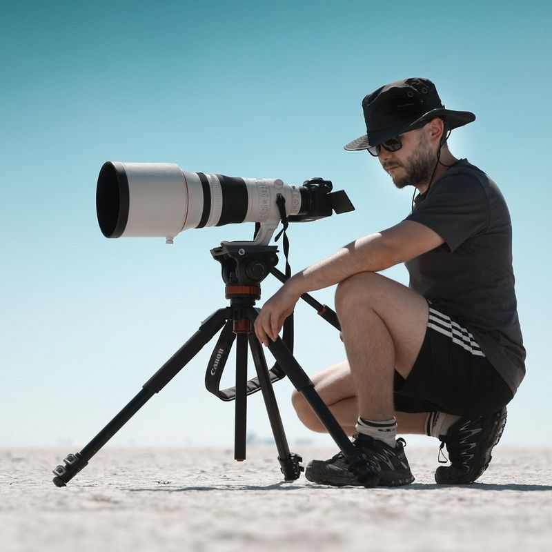 Canon Ambassador Burak Günaydın crouched behind a Canon camera on a tripod.