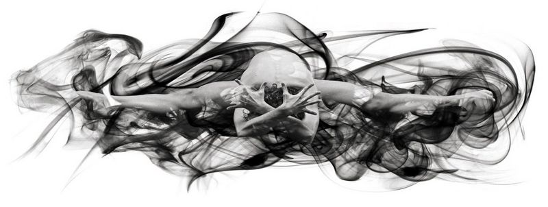 A seated ballet dancer with their legs spread wide and their head to the floor surrounded by swirling smoke. Taken on a Canon EOS-1Ds Mark III by Cem Talu.