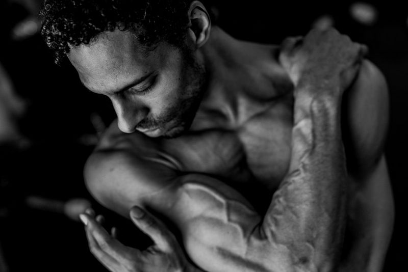 A close-up of the head and torso of a man wrapping his arms around his body.