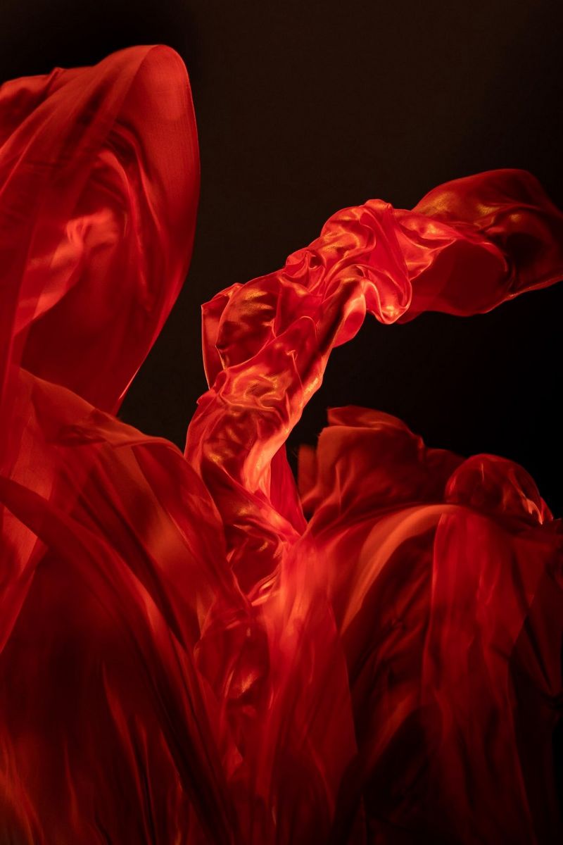 A dancer draped in red material that billows like a flame. 
