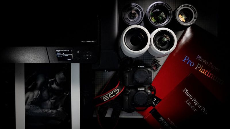 L'équipement de Clive Booth contenant des appareils photo, des objectifs, une imprimante et du papier pour imprimante Canon.