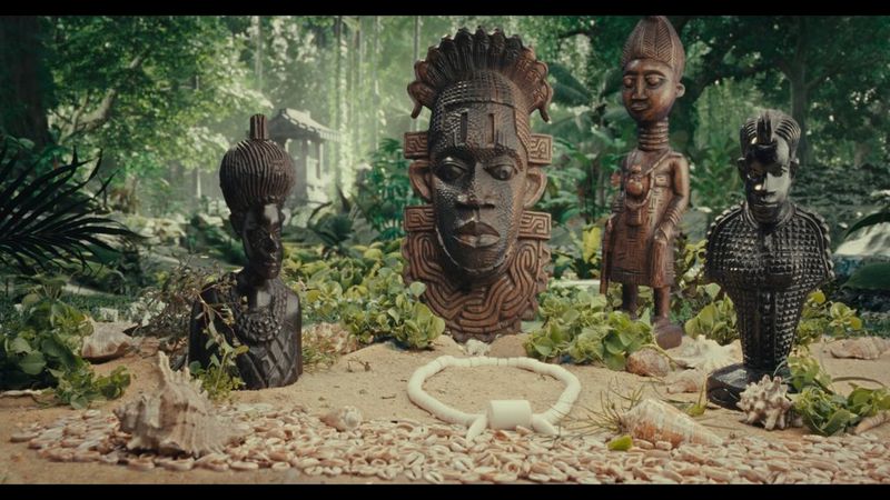 A still from footage shot by filmmaker Daniel Ehimen with a Canon CN-E50mm T1.3 L F lens showing African sculptures arranged in a jungle setting.