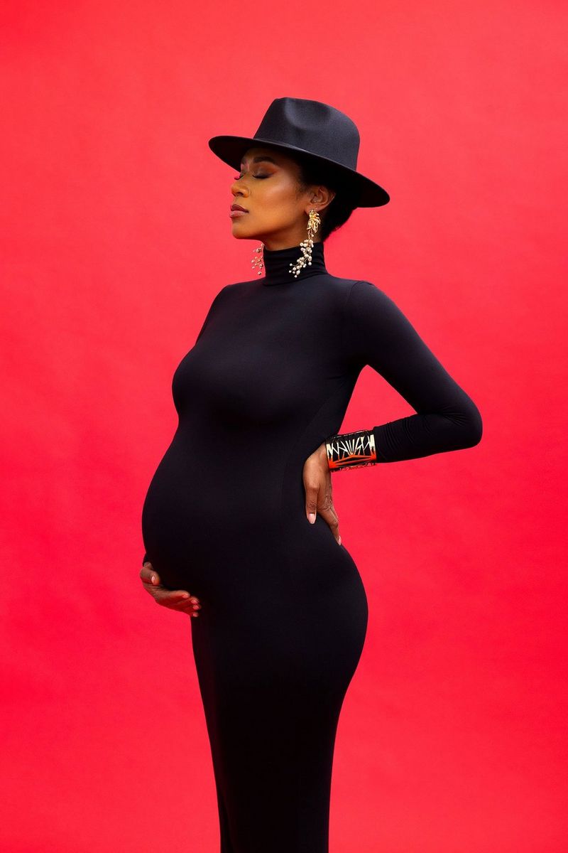 A portrait of a pregnant woman in a long, yellow off-the-shoulder dress that matches the colour of the background, taken on a Canon EOS R5 with a Canon RF 28-70mm F2L USM lens by Donatella Nicolini.
