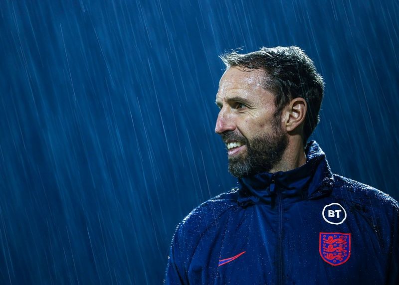 Gareth Southgate, manager of the England men's football team, standing smiling in the rain.