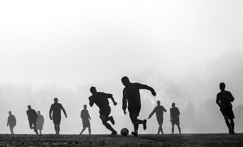 A black-and-white image of footballers playing on a misty day. 