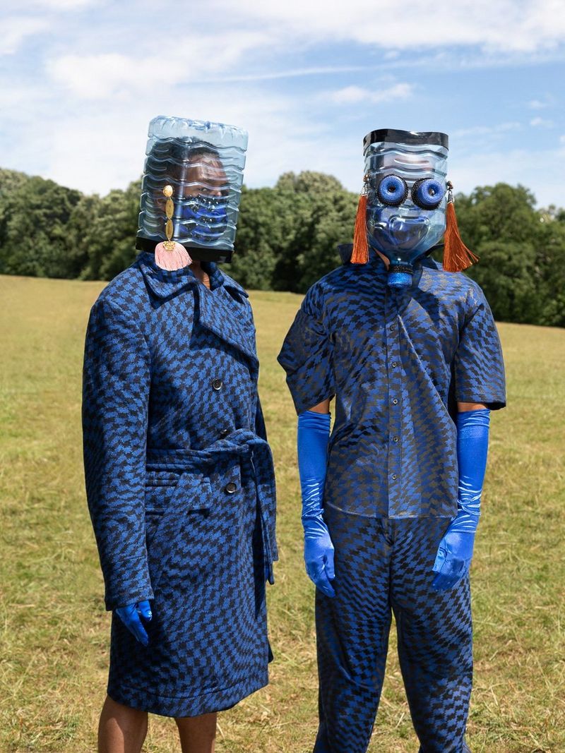 Two models dressed in blue wearing blue latex gloves and masks made of plastic water bottles. 