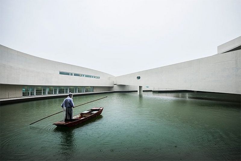 A man in protective clothing guides a boat through the water between the concrete structure of the Shihlien Chemical Plant in Huai'an, China.
