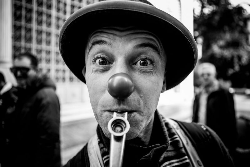 A black and white close-up photo of a street artist dressed as a clown, taken on the streets of Athens, Greece, by Canon Ambassador George Maschalidis.