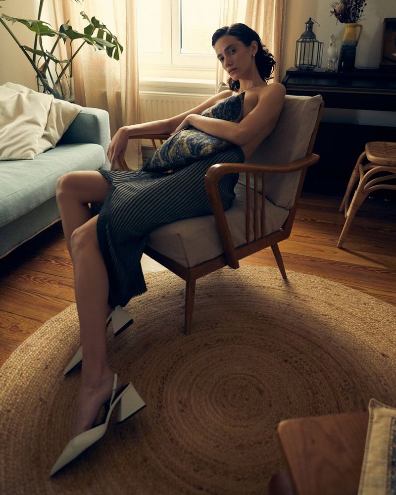 A model reclines in a wooden framed chair in a room lit from the window behind. Taken by Canon Ambassador Heidi Rondak