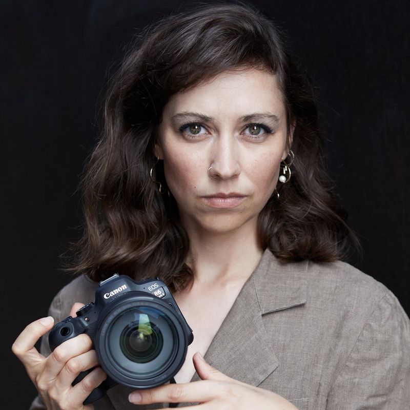 A portrait of Canon Ambassador Heidi Rondak holding a Canon EOS R6 Mark II camera, taken by Hannes Caspar.