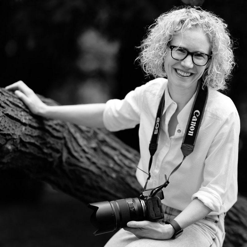 A black and white portrait of Canon Ambassador Helen Bartlett holding a Canon camera, taken by Tom Jenkins.