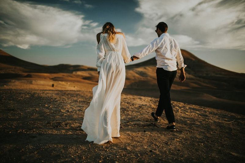 A bride and groom walking with their backs to the camera through a desert landscape. Taken by Igor Demba.