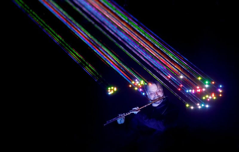 A flute player photographed during a rehearsal for a multimedia concert, multicoloured lasers pointing at him, in a photo taken by Canon Ambassador Ionut Macri.