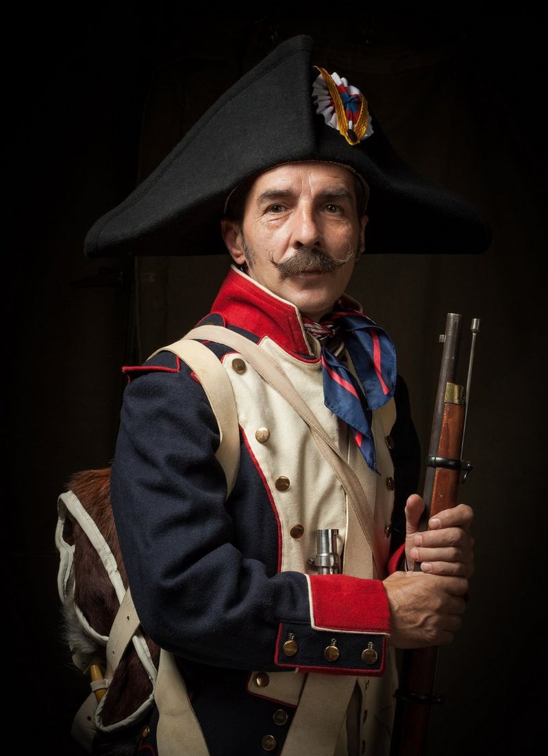 A man with a moustache dressed in a period costume stands against a black background and looks at the camera, in a photo taken by Canon Ambassador Ionut Macri.