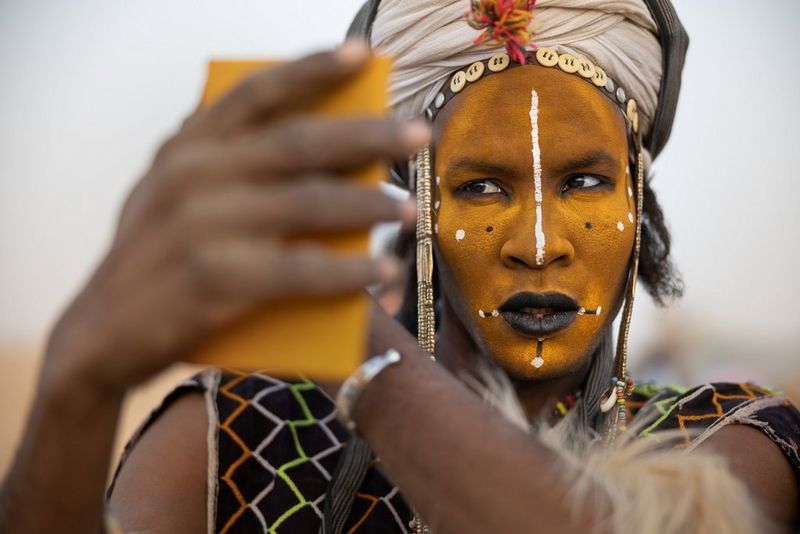 A Wodaabe tribesman wearing an elaborate headdress and with his face painted with black lines and white dots.