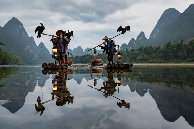 Elderly fishermen on rafts with lanterns and cormorants, on a lake in China. Photo by Joel Santos on a Canon EOS 5D Mark IV.