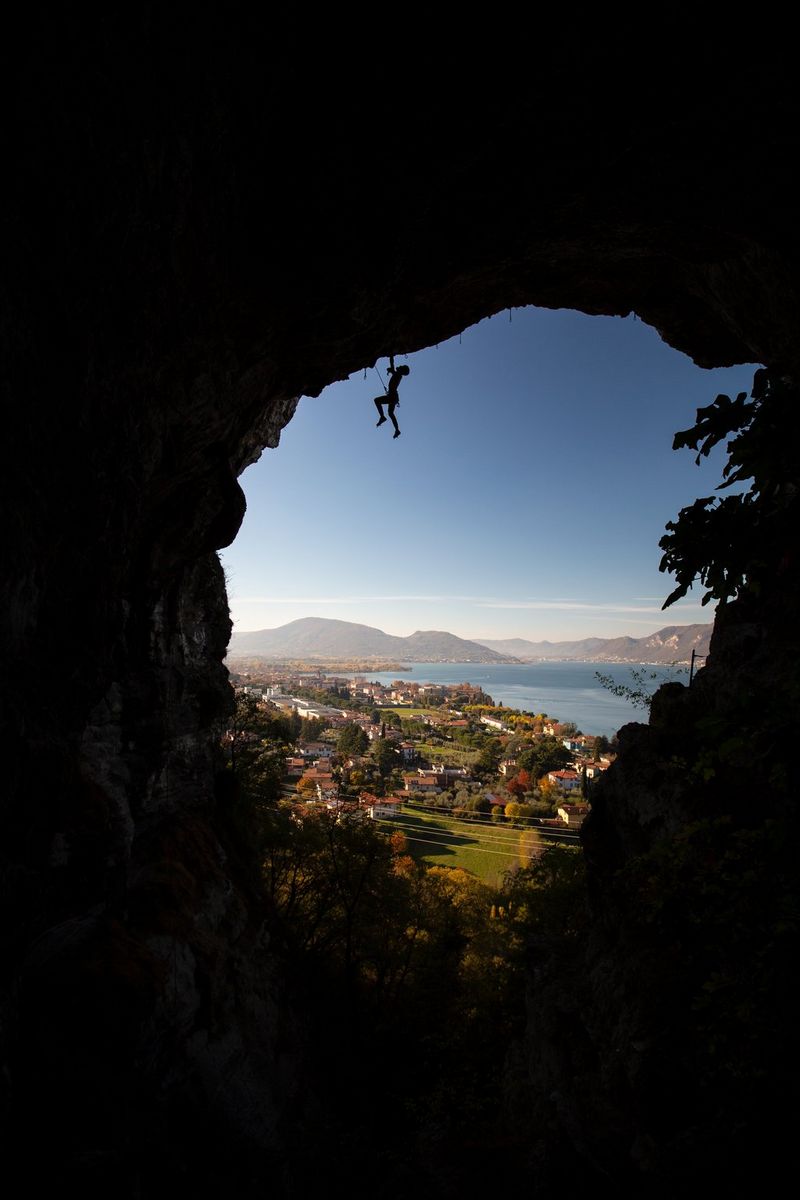 A climber hangs from an ice axe, embedded into the roof of a circular cave, which frames the lake and hills in the background. Taken by Canon Ambassador Julia Roger-Veyer.   