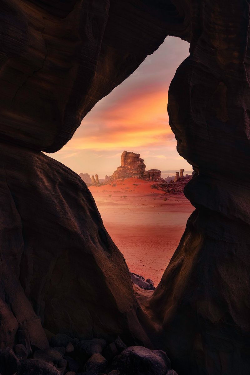 Through a hole in some rocks, rocks can be seen under an orange sky in the Sahara Desert in Algeria, taken on a Canon EOS R5 by Canon Ambassador Luka Vunduk. 