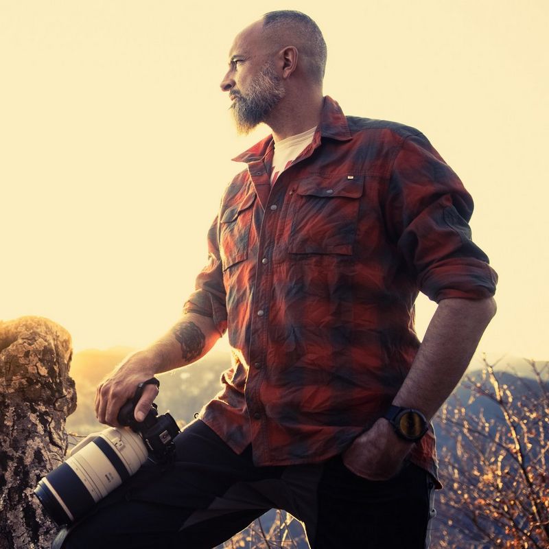 Canon Ambassador Luka Vunduk looks into the distance while holding a Canon camera in his hand.
