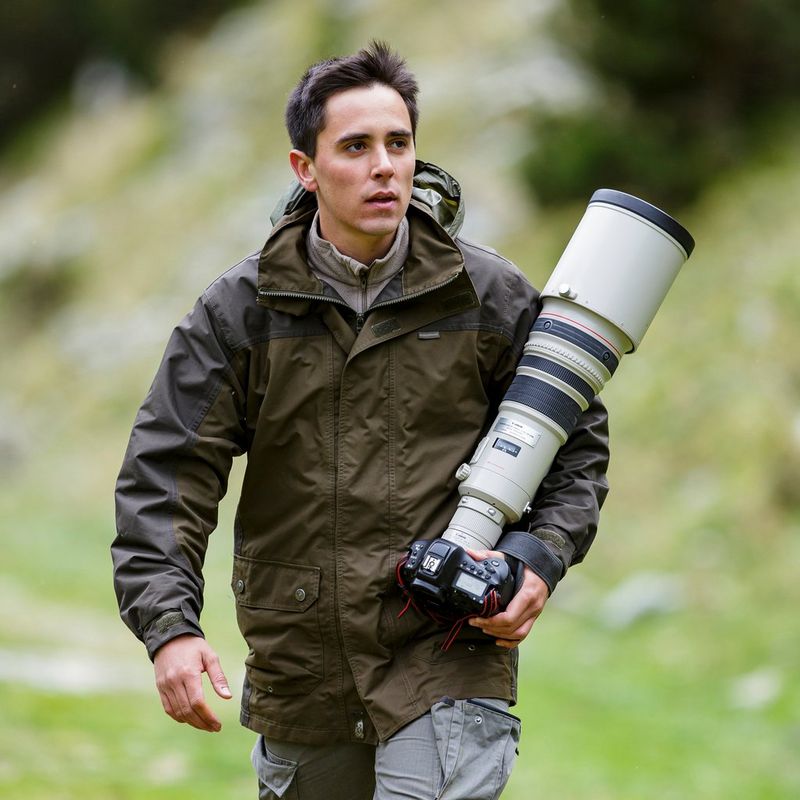 Wildlife photographer Marc Albiac carrying a Canon camera with a long lens attached.