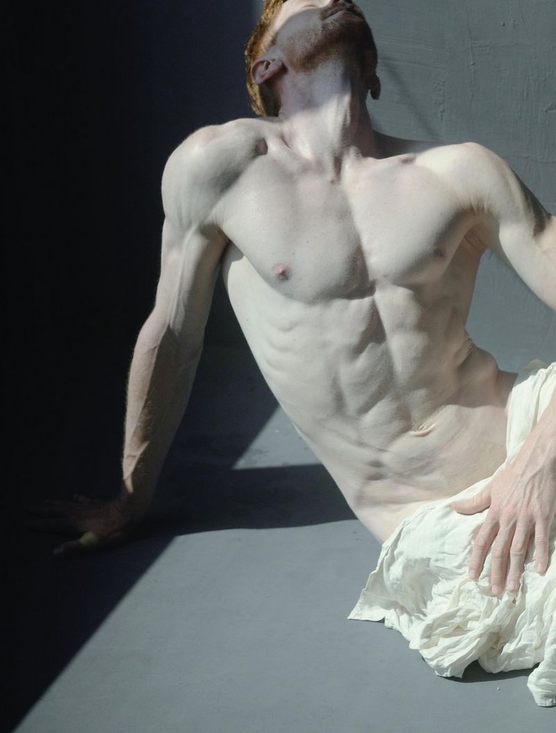 A painterly style portrait of a seated man, naked from the waist up, with his head thrown back.