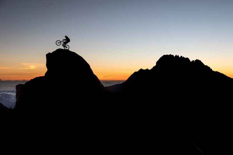 Silhouetted against the sunset, YouTube star and Red Bull rider Danny MacAskill hops on the back wheel of his mountain bike at the base camp of Mount Kilimanjaro.