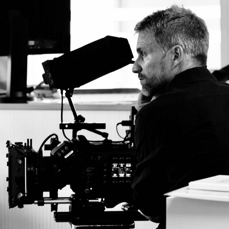 A black and white headshot of cinematographer Martin Christ filming with a Canon camera.