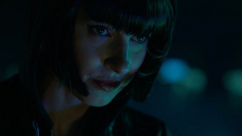 A woman's face is illuminated against a dark cityscape background in a still image from Martin Christ's futuristic sci-fi film KI – Die Letzte Erfindung.