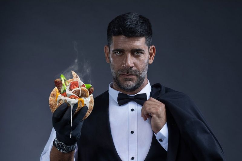 A man in a suit and bow tie holds a steaming kebab in a gloved hand in an image from a campaign shoot by Mor Tzidon taken on a Canon EOS R5.
