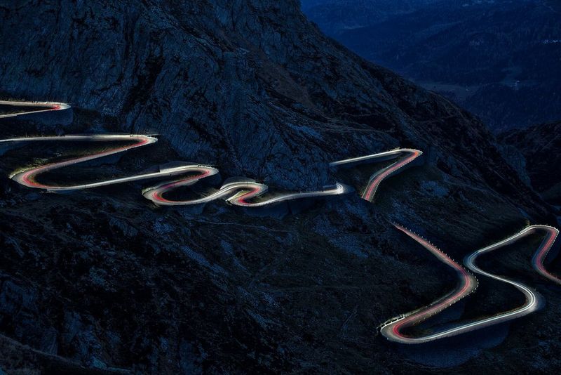 Car light trails in evening light down the side of a large mountain. Taken on a Canon EOS 5D Mark III by Nico Schaerer.